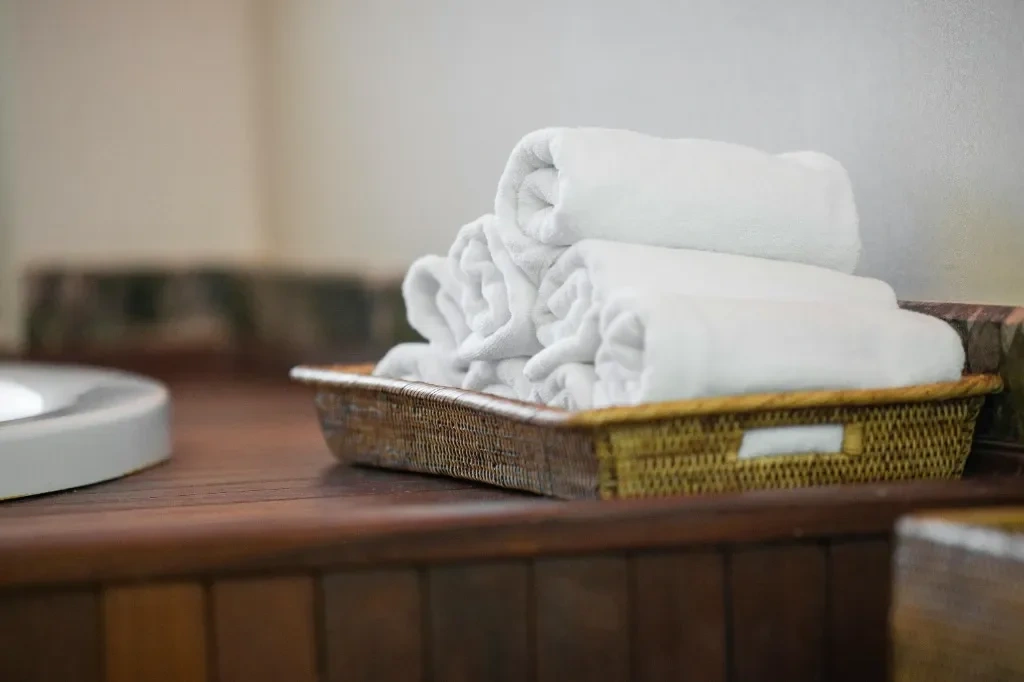 Pristine 5-star Airbnb turnover setup with premium rolled white towels in a basket, representing professional-grade hospitality standards.