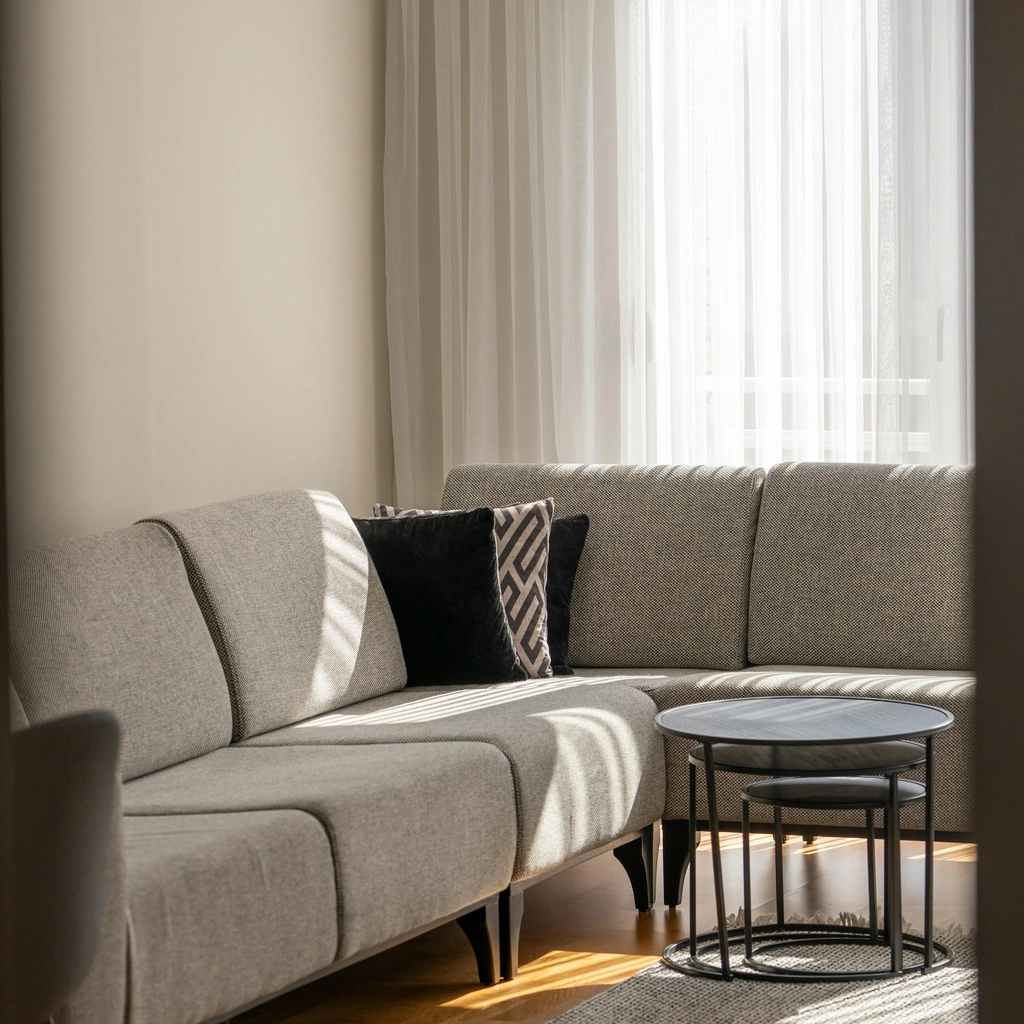 Professional Splash Maids cleaning specialist gently polishing a table in a bright, understated living room in a quiet residential neighborhood